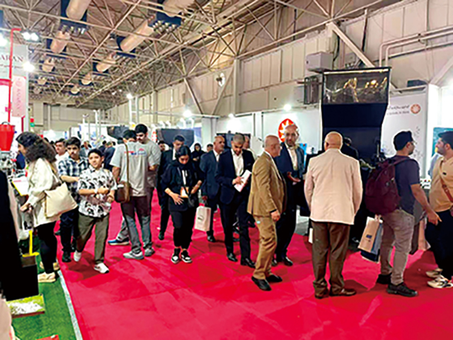 5.展館主通道人流密集，多位西裝革履的采購商正在觀看產品演示